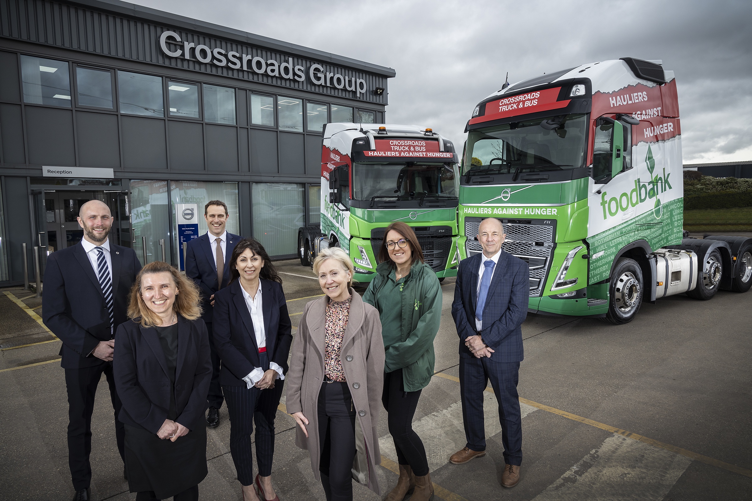 Gareth Legg (2nd from left) with Laura Chalmers (6th from left) with Crossroads staff and food bank volunteers in Rotherham. Photo 2 shows the Crossroads demonstrator trucks in Hauliers Against Hunger livery.  Issued by W1 Features on behalf of Crossroads.